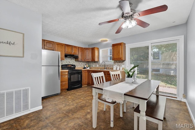 117 1st Ave, Edwardsville, IL 62025 - kitchen featuring freestanding refrigerator, black / electric stove, under cabinet range hood, brown cabinetry, and light countertops
