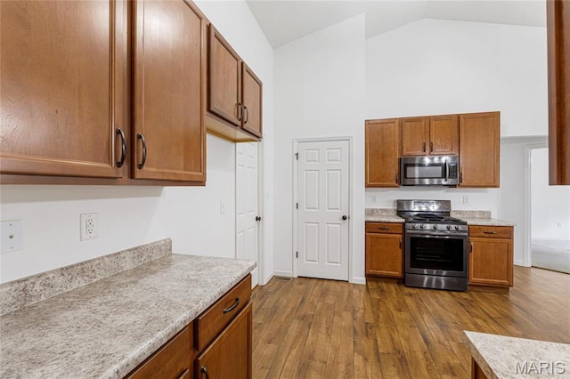 524 Pleasant Breeze Dr, Wentzville, MO 63385 - kitchen featuring stainless steel appliances, dark wood-type flooring, high vaulted ceiling, light countertops, and brown cabinetry