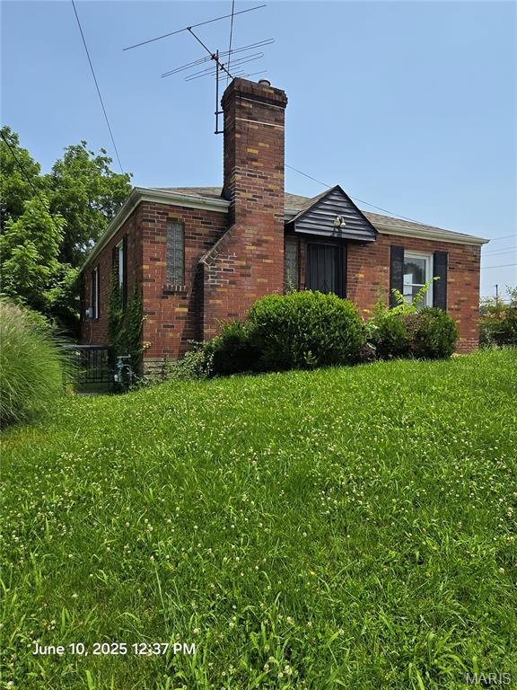 6203 Dardanella Ave, Normandy, MO 63121 - view of side of home featuring a chimney, brick siding, and a yard