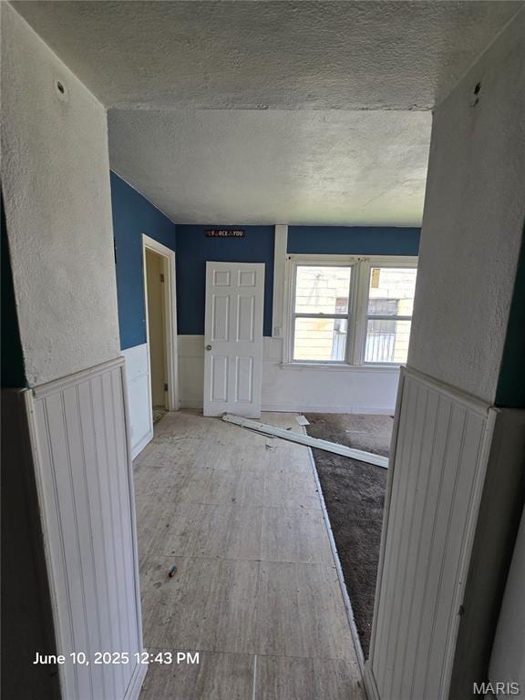 6203 Dardanella Ave, Normandy, MO 63121 - hallway featuring a textured ceiling and a wainscoted wall