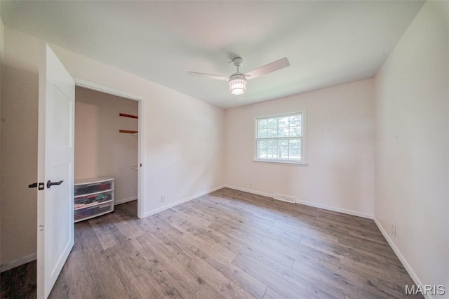 12575 State Route F, Rolla, MO 65401 - unfurnished bedroom featuring wood finished floors, ceiling fan, and a walk in closet