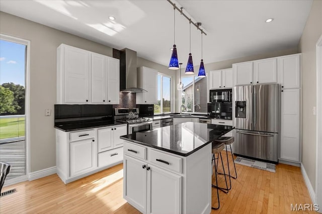 612 Thornridge Dr, Ofallon, MO 63368 - kitchen with stainless steel appliances, wall chimney range hood, tasteful backsplash, a breakfast bar, and recessed lighting