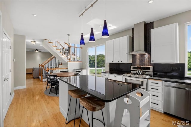 612 Thornridge Dr, Ofallon, MO 63368 - kitchen with stainless steel appliances, wall chimney exhaust hood, backsplash, a kitchen island, and white cabinetry