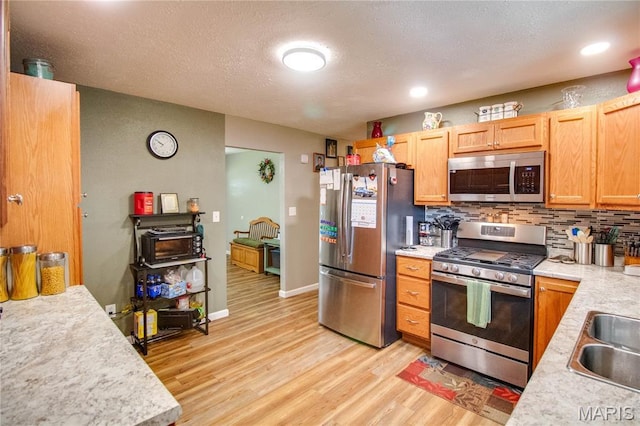 109 Hawbrook Pl, Jerseyville, IL 62052 - kitchen with appliances with stainless steel finishes, light countertops, light wood finished floors, decorative backsplash, and a textured ceiling