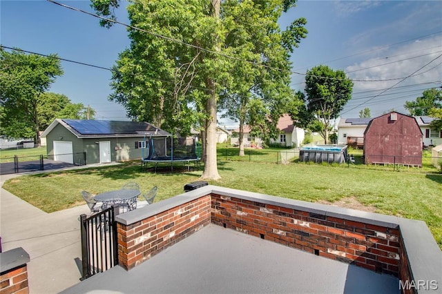 109 Hawbrook Pl, Jerseyville, IL 62052 - view of patio / terrace with a trampoline, an outdoor structure, a detached garage, concrete driveway, and outdoor dining space