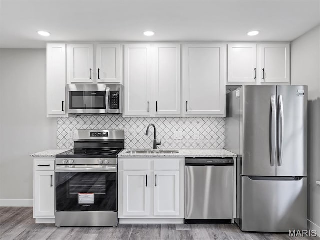 1505 Cypress Dr, Pacific, MO 63069 - kitchen featuring stainless steel appliances, white cabinets, light stone countertops, light wood-type flooring, and recessed lighting