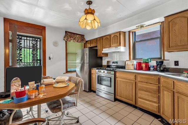 5447 Claxton Ave, Saint Louis, MO 63120 - kitchen featuring appliances with stainless steel finishes, under cabinet range hood, decorative backsplash, light tile patterned floors, and brown cabinets