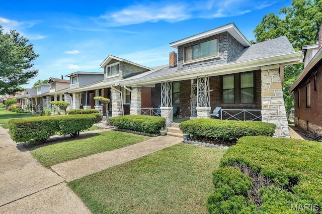 5447 Claxton Ave, Saint Louis, MO 63120 - view of front of house featuring a front lawn, stone siding, covered porch, and a shingled roof