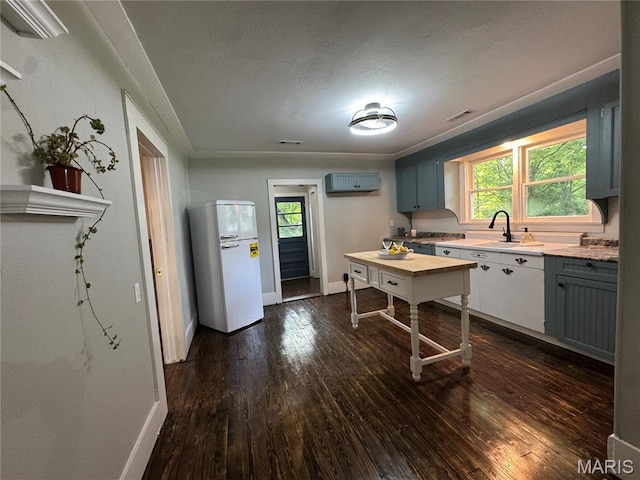 719 N 10th St, Poplar Bluff, MO 63901 - kitchen with fridge, dark wood-style floors, light countertops, gray cabinets, and a textured ceiling