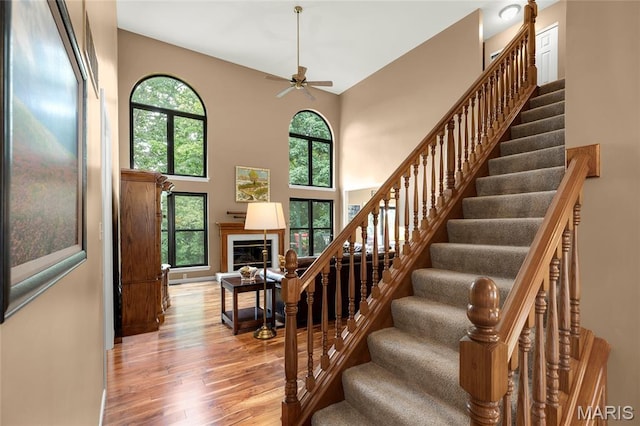 2260 Crimson View Dr, Wildwood, MO 63011 - stairway featuring wood finished floors, a ceiling fan, healthy amount of natural light, a glass covered fireplace, and a towering ceiling