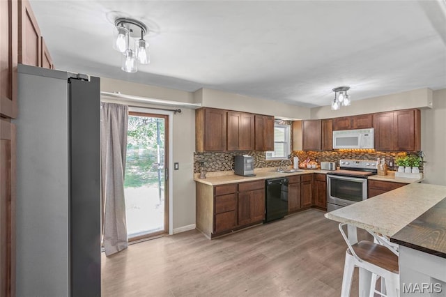 1117 Nelda Dr, Imperial, MO 63052 - kitchen featuring stainless steel appliances, tasteful backsplash, light wood-type flooring, and plenty of natural light