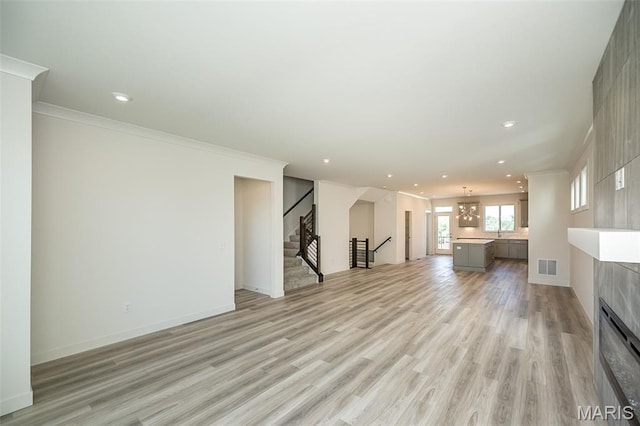 8971 Eager Rd, Richmond Heights, MO 63144 - unfurnished living room with light wood finished floors, stairs, recessed lighting, a tile fireplace, and ornamental molding