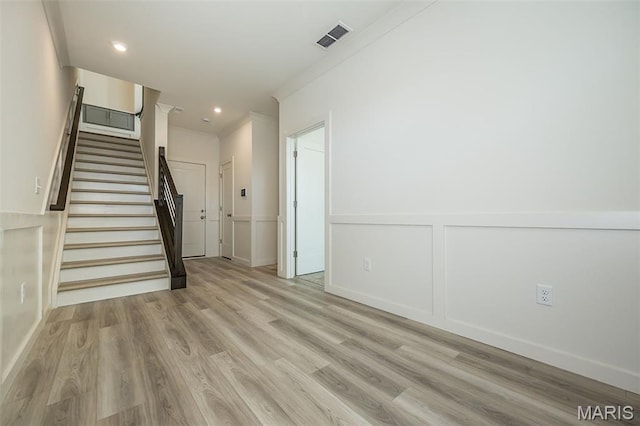 8971 Eager Rd, Richmond Heights, MO 63144 - unfurnished living room featuring light wood-style floors, stairs, ornamental molding, recessed lighting, and a decorative wall
