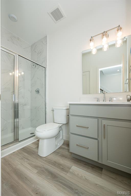 8971 Eager Rd, Richmond Heights, MO 63144 - full bathroom with vanity, a marble finish shower, and wood finished floors