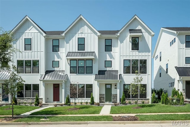 8971 Eager Rd, Richmond Heights, MO 63144 - view of front facade featuring a standing seam roof, stone siding, a front lawn, and board and batten siding