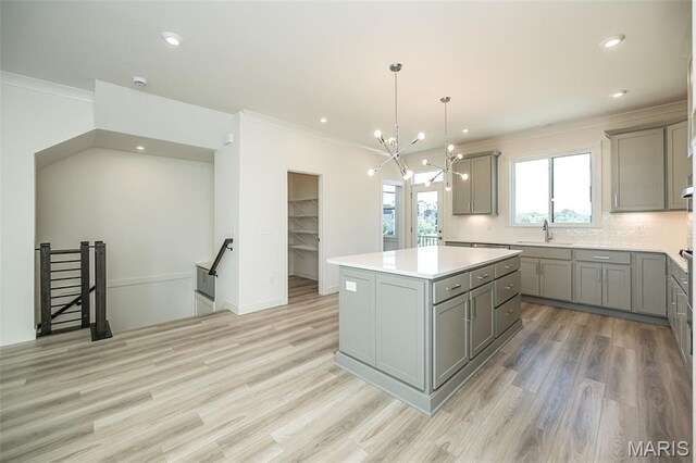 8971 Eager Rd, Richmond Heights, MO 63144 - kitchen with gray cabinetry, ornamental molding, a kitchen island, light wood finished floors, and tasteful backsplash