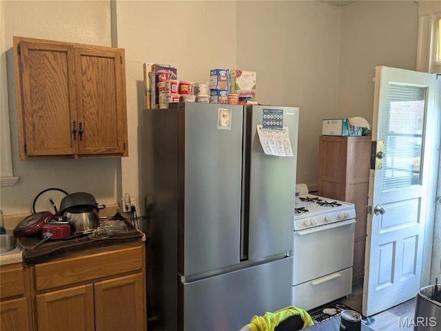 3744 Michigan Ave, Saint Louis, MO 63118 - kitchen with freestanding refrigerator, white gas range oven, brown cabinetry, and dark countertops