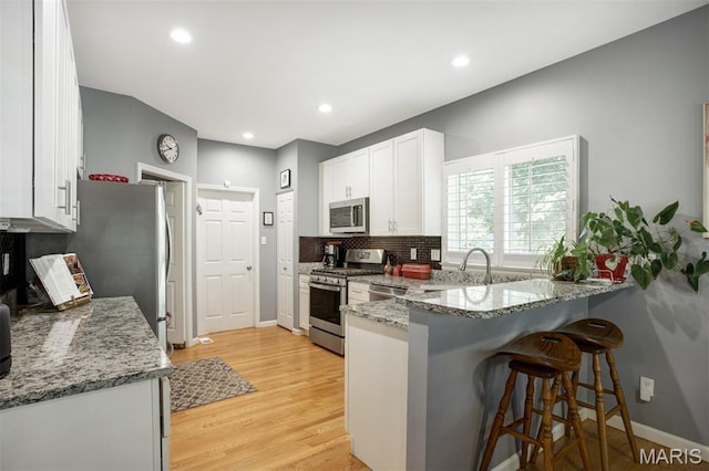 1168 Oak Knoll Manor Ct, Saint Louis, MO 63119 - kitchen with stainless steel appliances, a peninsula, a breakfast bar, light stone countertops, and white cabinets