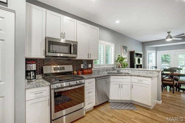 1168 Oak Knoll Manor Ct, Saint Louis, MO 63119 - kitchen featuring appliances with stainless steel finishes, a peninsula, light wood-style flooring, white cabinets, and recessed lighting
