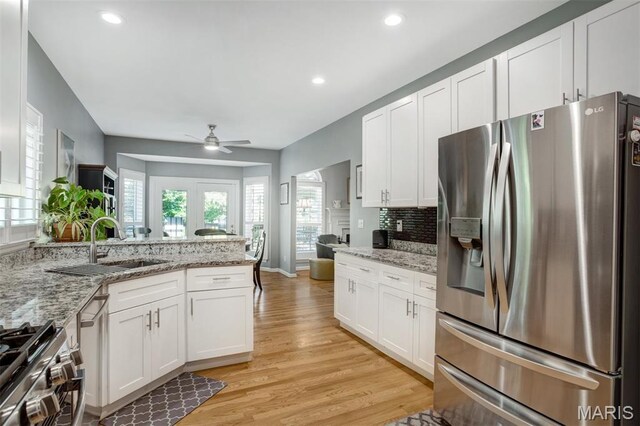 1168 Oak Knoll Manor Ct, Saint Louis, MO 63119 - kitchen with stainless steel appliances, white cabinets, light wood-style floors, a peninsula, and a ceiling fan