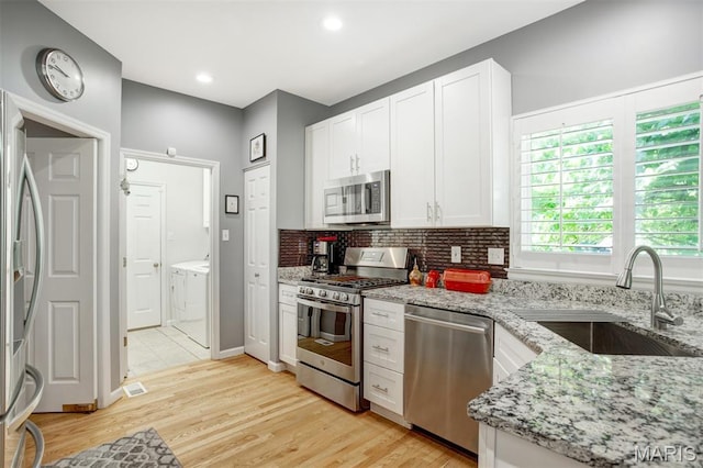 1168 Oak Knoll Manor Ct, Saint Louis, MO 63119 - kitchen featuring stainless steel appliances, independent washer and dryer, light stone counters, tasteful backsplash, and white cabinets