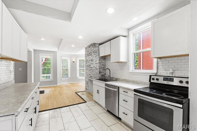5829 Bartmer Ave, Saint Louis, MO 63112 - kitchen with appliances with stainless steel finishes, light countertops, white cabinets, light marble finish flooring, and tasteful backsplash
