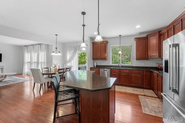 1412 Heritage Valley Dr, High Ridge, MO 63049 - kitchen featuring appliances with stainless steel finishes, wood finished floors, a center island, hanging light fixtures, and recessed lighting