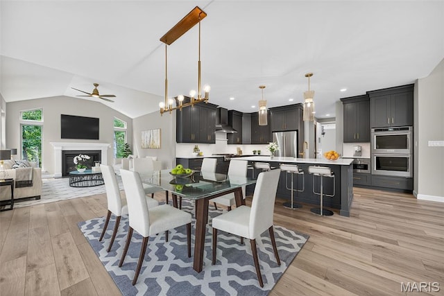 212 Terradel Trl, Foristell, MO 63348 - dining space with light wood-style flooring, a ceiling fan, a fireplace, lofted ceiling, and recessed lighting