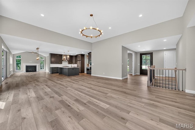 212 Terradel Trl, Foristell, MO 63348 - unfurnished living room with a chandelier, light wood-style floors, recessed lighting, vaulted ceiling, and a fireplace