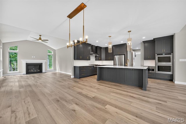 212 Terradel Trl, Foristell, MO 63348 - kitchen with stainless steel appliances, light countertops, a ceiling fan, wall chimney exhaust hood, and light wood-style flooring