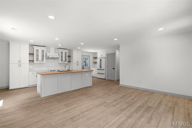 715 Westchester Ct, Kirkwood, MO 63122 - kitchen featuring open shelves, wood counters, under cabinet range hood, a center island with sink, and recessed lighting