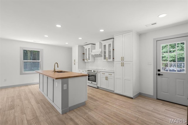 715 Westchester Ct, Kirkwood, MO 63122 - kitchen featuring high end range, butcher block counters, backsplash, a kitchen island with sink, and light wood-style flooring