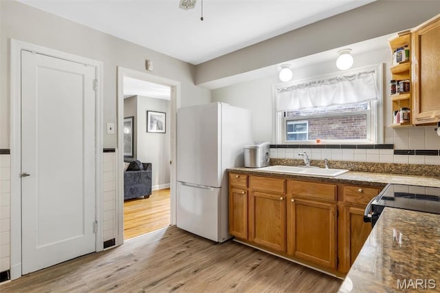 1164 Ursula Ave, University City, MO 63130 - kitchen featuring freestanding refrigerator, light wood-style floors, brown cabinets, decorative backsplash, and electric range