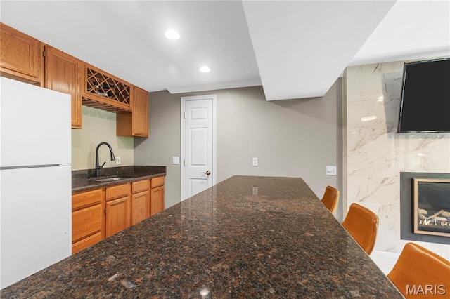 391 Carriage Trail Ct, Ofallon, MO 63368 - kitchen with freestanding refrigerator, recessed lighting, dark stone countertops, and brown cabinets