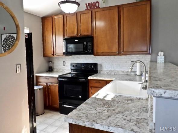 7302 Spring Creek Ln, Ofallon, MO 63368 - kitchen with black appliances, brown cabinetry, backsplash, and light countertops