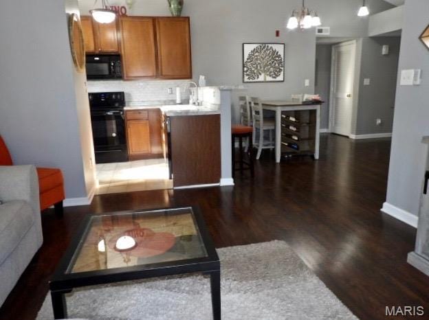 7302 Spring Creek Ln, Ofallon, MO 63368 - kitchen featuring brown cabinets, range, dark wood-style floors, tasteful backsplash, and black microwave