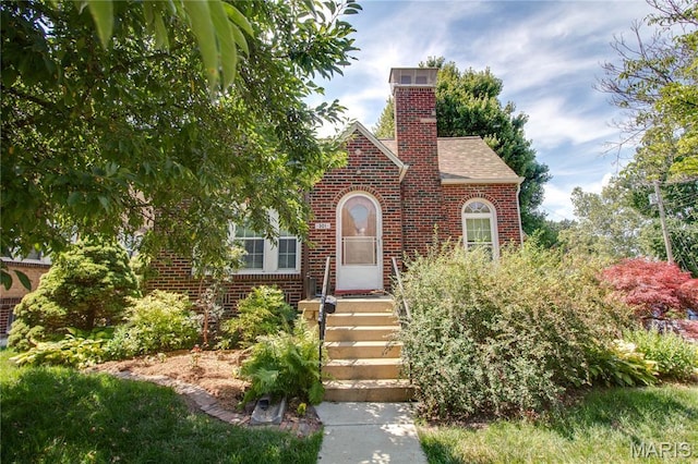 301 E 7th St, Alton, IL 62002 - tudor house featuring brick siding, a shingled roof, and a chimney