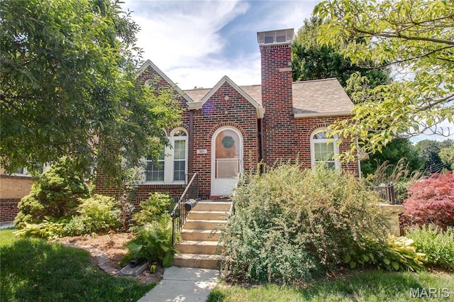 301 E 7th St, Alton, IL 62002 - tudor home featuring brick siding, roof with shingles, and a chimney