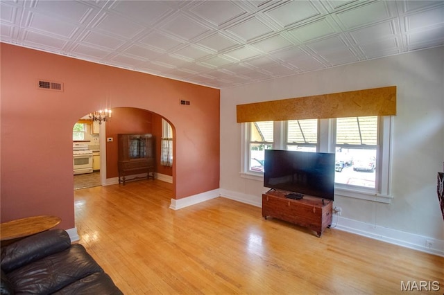 301 E 7th St, Alton, IL 62002 - living area featuring arched walkways, healthy amount of natural light, light wood-style flooring, an ornate ceiling, and a chandelier