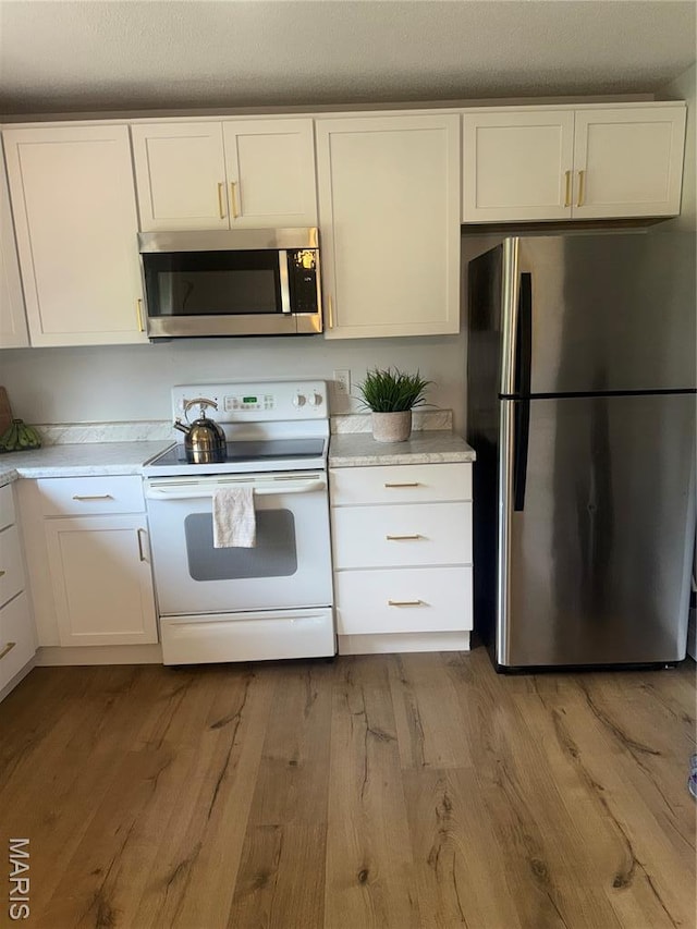 24 Lantern Ln, Lake St Louis, MO 63367 - kitchen featuring appliances with stainless steel finishes, light wood finished floors, and white cabinets