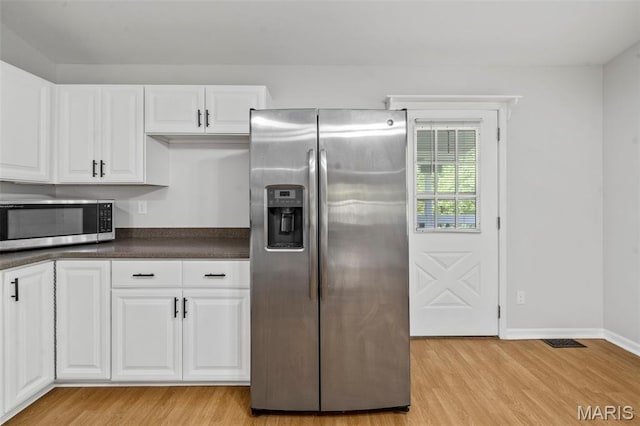 5265 Country Club Rd, Washington, MO 63090 - kitchen featuring appliances with stainless steel finishes, light wood-style flooring, dark countertops, and white cabinets