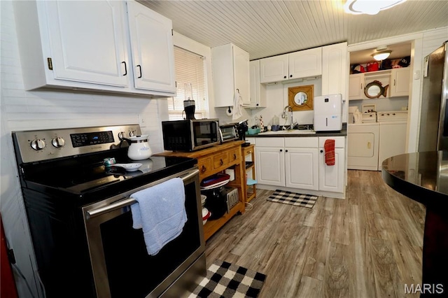 980 Laura Hufferd Rd, Roach, MO 65787 - kitchen featuring appliances with stainless steel finishes, washing machine and clothes dryer, white cabinetry, and light wood-style floors