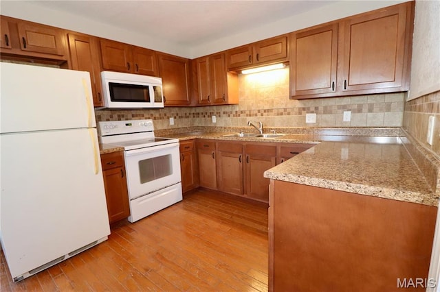 261 Buffalo Linn Creek Rd, Macks Creek, MO 65786 - kitchen featuring white appliances, brown cabinetry, tasteful backsplash, light wood-style flooring, and light stone counters