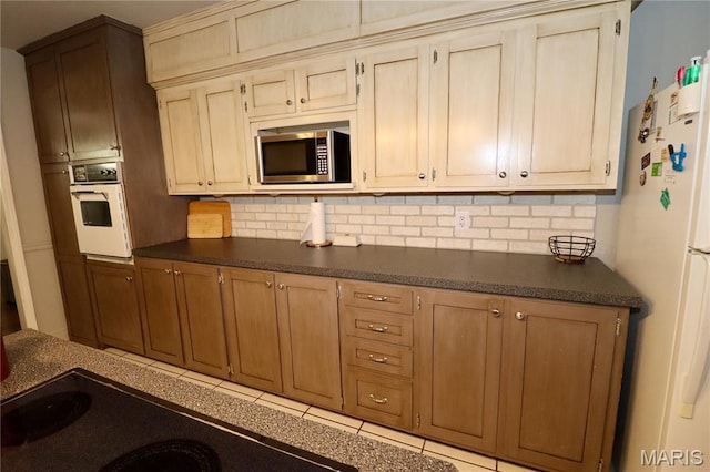 110 S Bend Rd, Lebanon, MO 65536 - kitchen featuring white appliances, dark countertops, tasteful backsplash, and tile patterned flooring