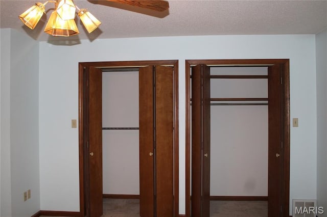 904 Keith St, Kennett, MO 63857 - unfurnished bedroom featuring two closets, a textured ceiling, and a ceiling fan