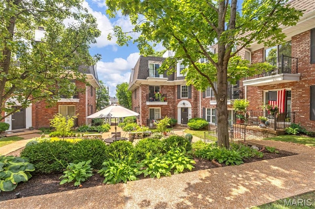 115 E Bodley Ave Unit A6, Kirkwood, MO 63122 - view of front of house with brick siding, a balcony, mansard roof, and a shingled roof