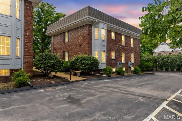 115 E Bodley Ave Unit A6, Kirkwood, MO 63122 - view of side of property with brick siding, mansard roof, uncovered parking, and a shingled roof