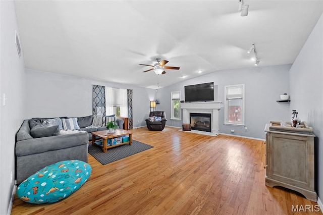 1745 Woodwind Dr, Imperial, MO 63052 - living area featuring rail lighting, ceiling fan, light wood-style flooring, vaulted ceiling, and a glass covered fireplace