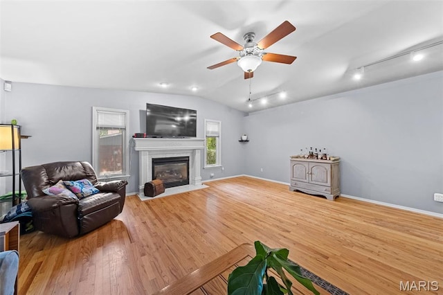 1745 Woodwind Dr, Imperial, MO 63052 - living room featuring a ceiling fan, vaulted ceiling, wood finished floors, a fireplace with flush hearth, and rail lighting