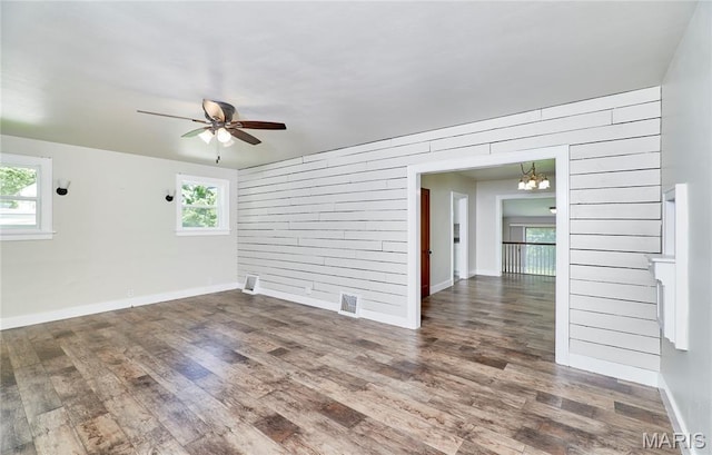 900 3rd St, Troy, MO 63379 - empty room featuring wood finished floors, wooden walls, ceiling fan, and plenty of natural light